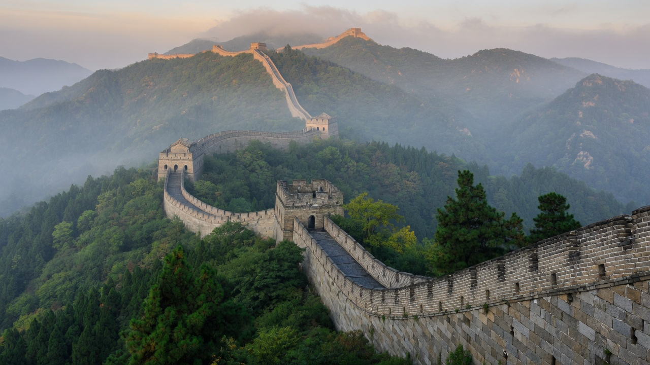 The Great Wall of China running along forested ridges in morning mist