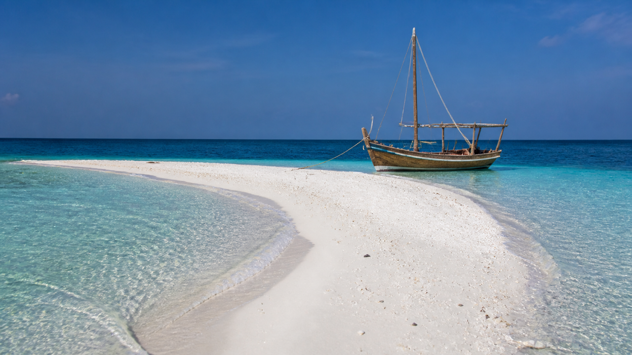 A traditional dhoni boat anchored in a turquoise Maldivian lagoon