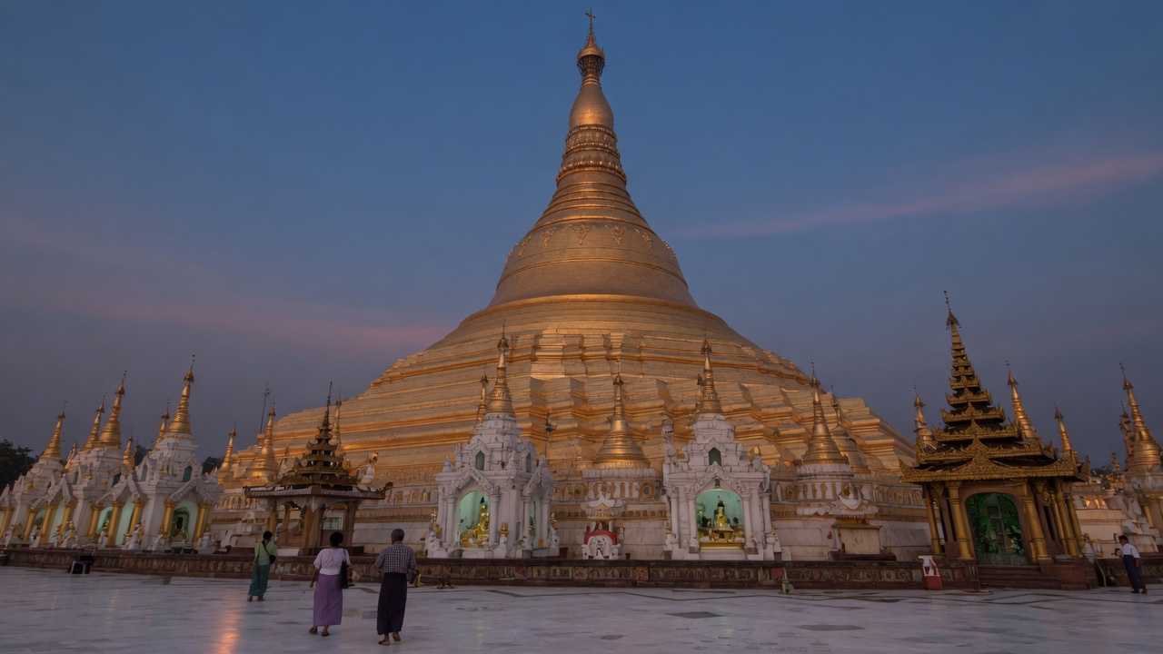 The gilded Shwedagon Pagoda in Yangon glowing against a deep blue evening sky